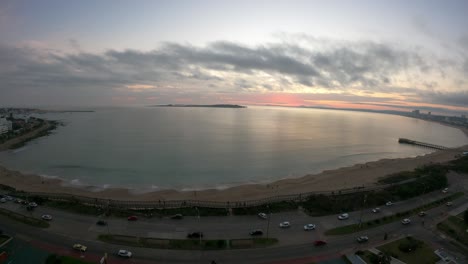 Timelapse-Aéreo-De-La-Hermosa-Puesta-De-Sol-En-El-Horizonte-En-La-Playa-De-Punta-Del-Este,-Uruguay---Tráfico-En-La-Carretera-Por-La-Noche