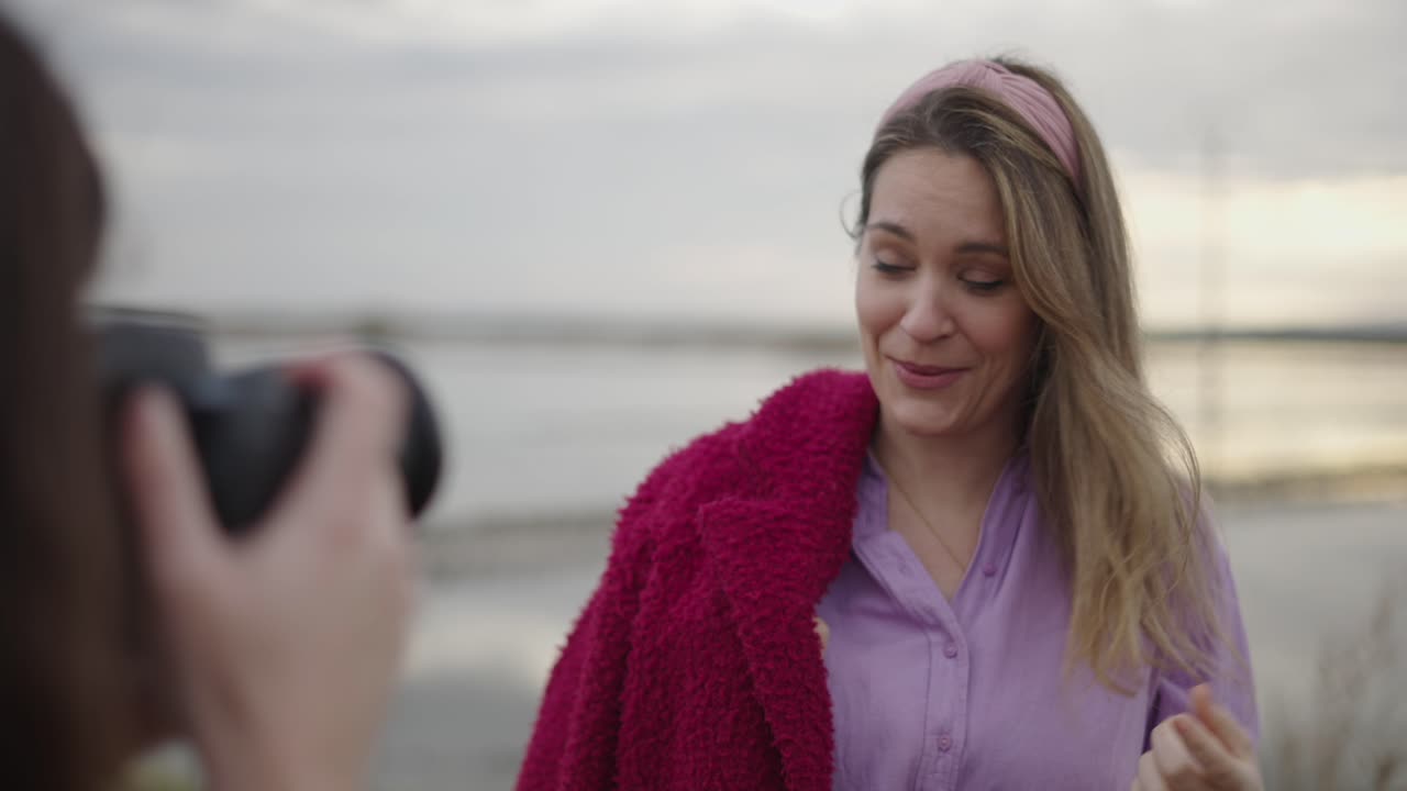 Woman being photographed by a friend near a body of water