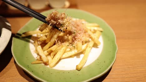 chopsticks picking up fries from a plate