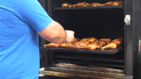 man checking the temperature of bbq chicken in an off set bbq smoker