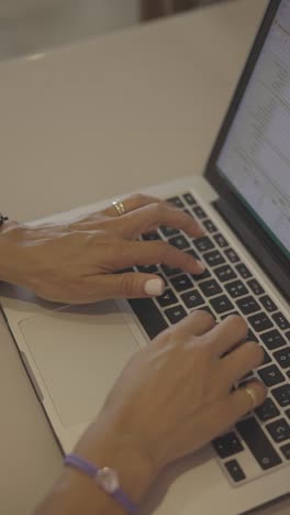 female hands typing on laptop at desk, close up view