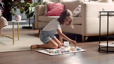 blonde girl sitting on the floor and painting animal pieces in living room