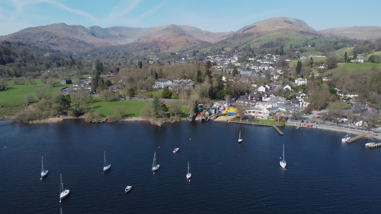 Cinematic drone video retreating from Ambleside town on Windermere with Fairfield Horseshoe fells in the background