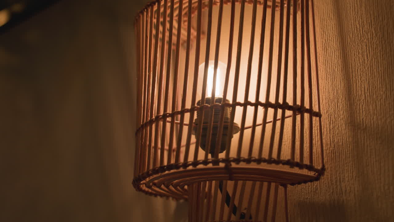 close up decorative wall light with wooden slats glowing warmly, casting soft shadow patterns on textured wall, creating cozy and artistic ambiance in indoor setting with warm tones