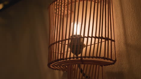close up decorative wall light with wooden slats glowing warmly, casting soft shadow patterns on textured wall, creating cozy and artistic ambiance in indoor setting with warm tones
