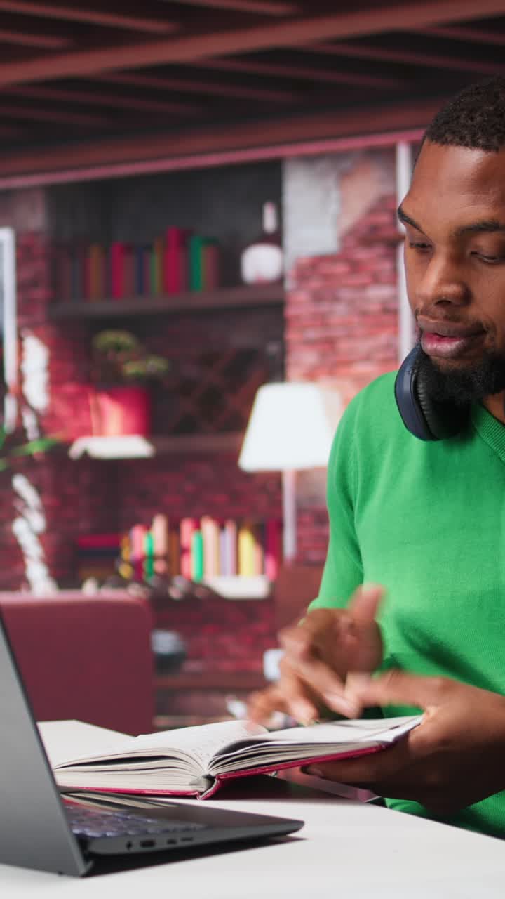 Vertical Video African american male teleworker writing personal notes at his desk