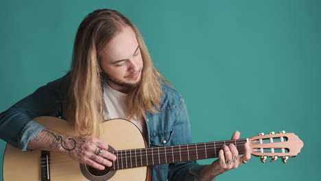 caucasian young man playing guitar on camera.