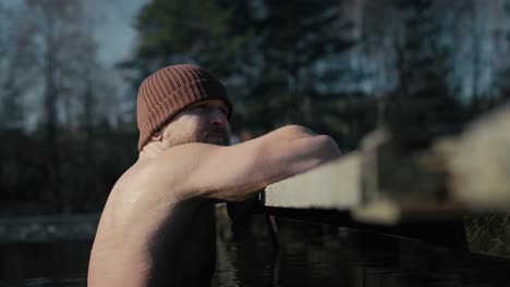 caucasian adult man swimming in frozen lake.