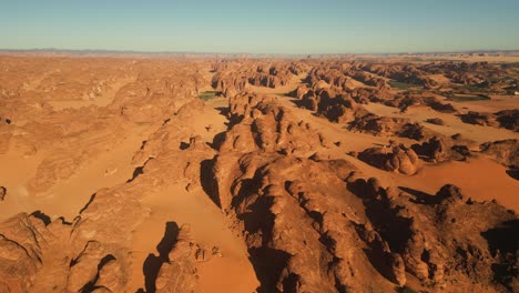 Fly-above-rock-formation-mountains-in-desert-near-Al-Ula,-Saudi-Arabia-at-sunset