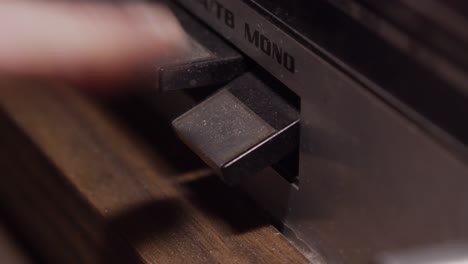 closeup, finger pushes down button on dusty old radio