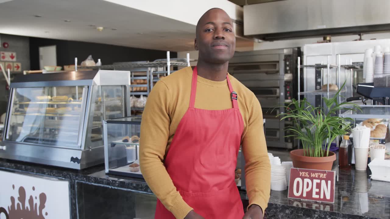retrato de un feliz trabajador afroamericano con los brazos cruzados en una panadería en cámara lenta