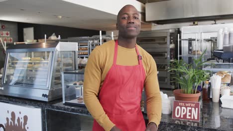 Portrait-of-happy-african-american-male-worker-with-arms-crossed-in-bakery-in-slow-motion