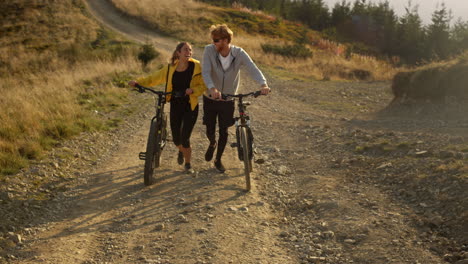 Girl-and-guy-with-bikes-going-on-road-Cyclists-taking-rest-after-exercising