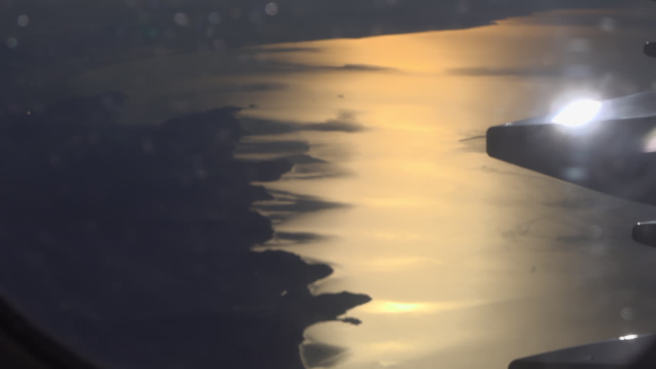 View from an airplane window of the sunset reflecting on the sea