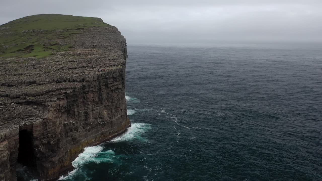 Aerial view along Faroe Islands sea cliffs and waterfall, Atlantic coast