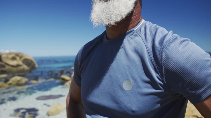 Uomo afroamericano anziano che si riposa durante l'esercizio, ammirando la vista mare.