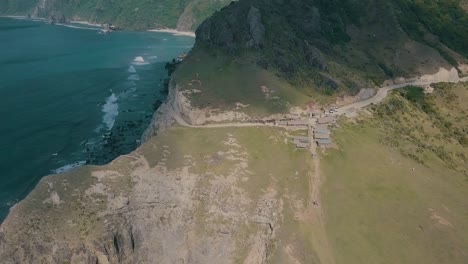 Cinematic-aerial-drone-video-of-splashing-ocean-waves-into-a-scenic-mountains-of-Sabtang,-Batanes-in-the-Philippines