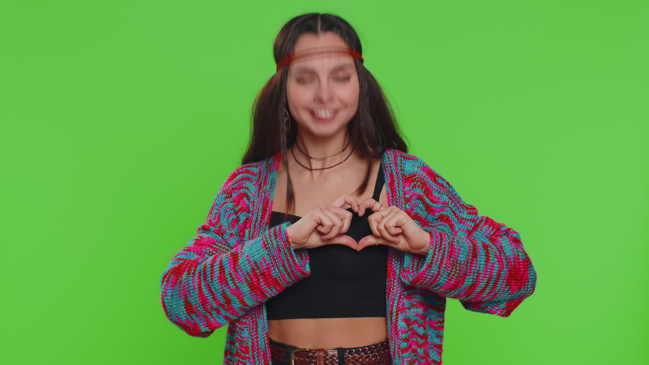 Smiling hippie woman makes heart gesture demonstrates love sign expresses good feelings and sympathy