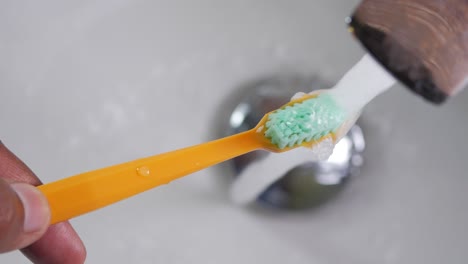 closeup of a toothbrush being rinsed under a faucet