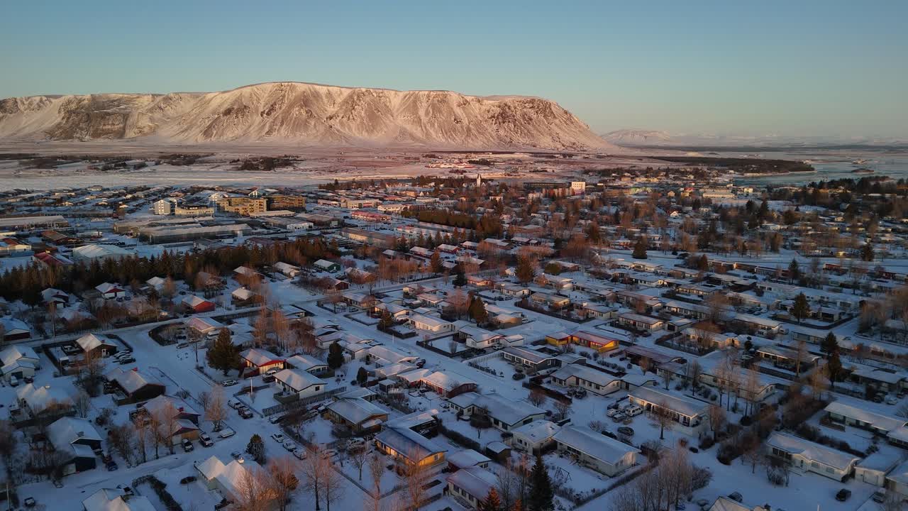 ciudad de invierno nevada de selfoss con el río ölfusa y la montaña nevada en la distancia. nieve de invierno en el vecindario islandés con coches en la carretera. drone wide shot. dolly.