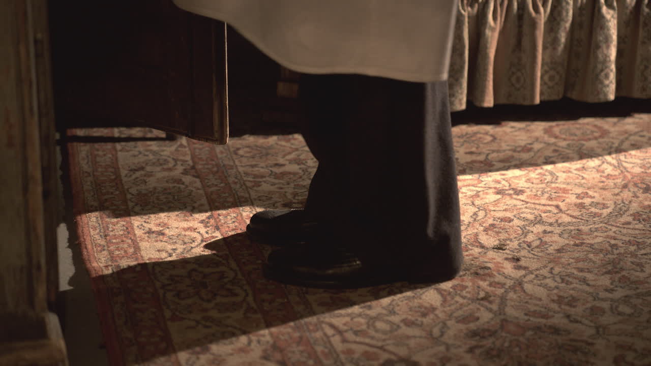 Men's black vintage shoes walk over an old carpet toward a wooden box, retro 1950s atmosphere