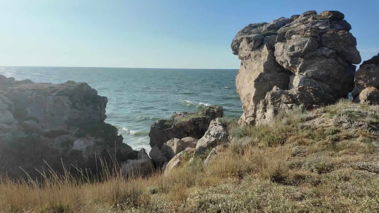 파도가 크리미아의 바위 해안에 부히며, 은 날 아조프 해 근처의 자연의 아름다움과 거친 풍경을 강조합니다.