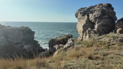 waves crash against the rocky shoreline of crimea, highlighting the natural beauty and rugged landscape near the sea of azov during a clear day