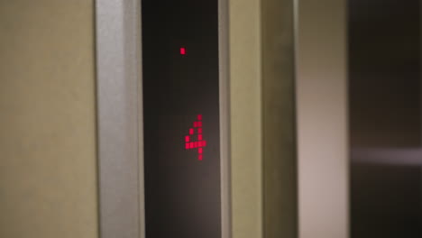 elevator display showing downward arrow and floor 4, digital red indicator, modern elevator system, business building, corporate setting, elevator in motion, office environment