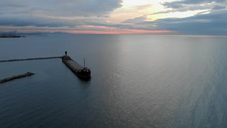 drone flying around a large ship docked at a harbor at sunrise in mississauga