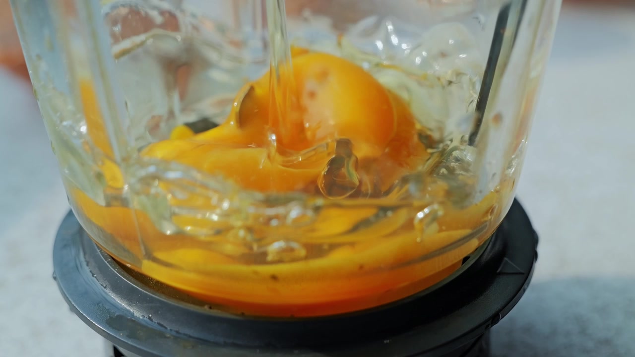 Golden yolk and clear egg white cascade into blender creating dynamic motion