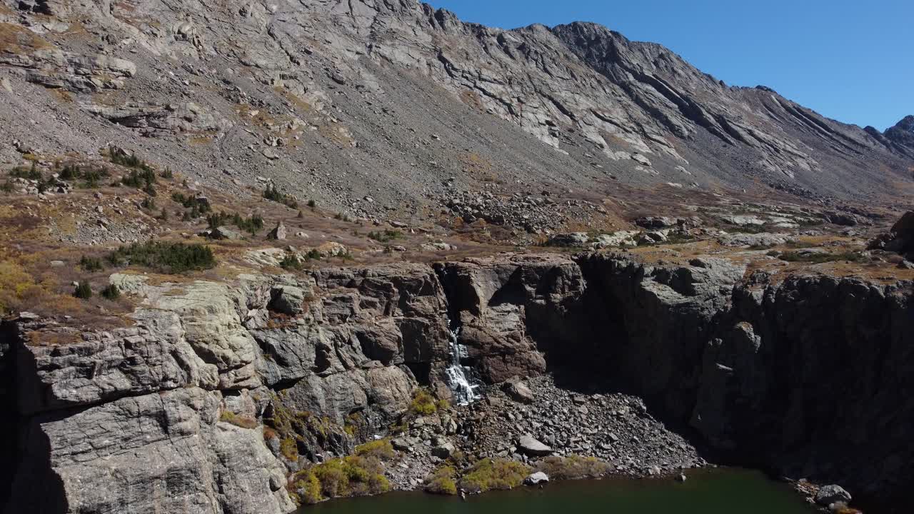 descendiendo sobre el lago de montaña de colorado con la cascada del lago willow en la distancia, aérea