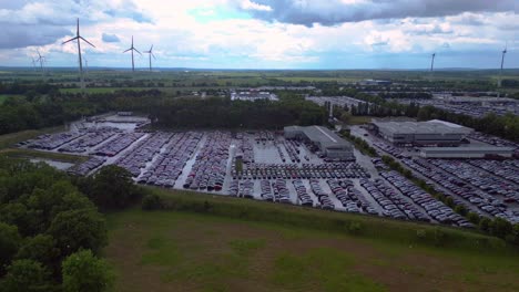 large parking lot full of cars near a wind farm and countryside in germany. nice raining aerial view flight panorama overview drone
