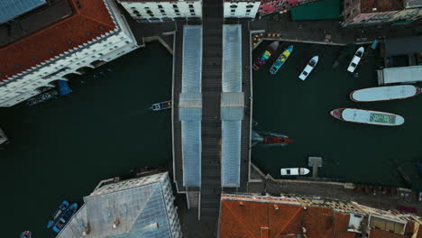 top down view of rialto bridge with boats and gondolas passing under on grand canal, venice, italy - drone shot