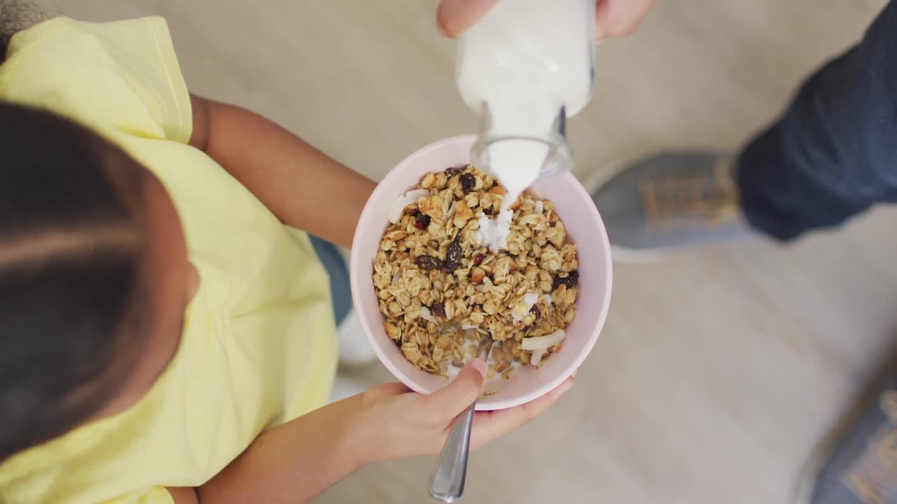 Padre e figlia birazziali felici che preparano la colazione insieme