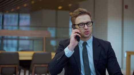 cheerful businessman young man in an office making a phone call