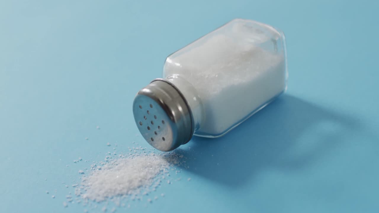Video of salt in a salt shaker on blue background