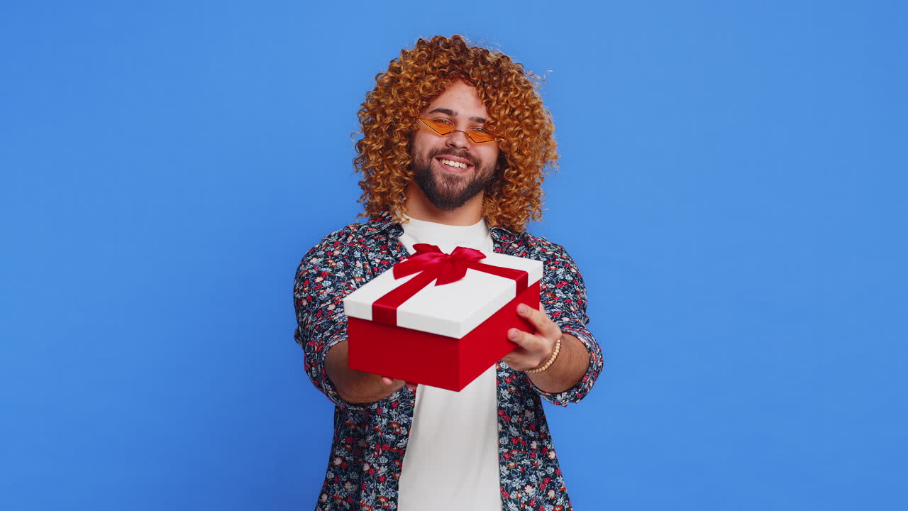 Smiling young man presenting birthday gift present box stretches out hands promotion discount sale