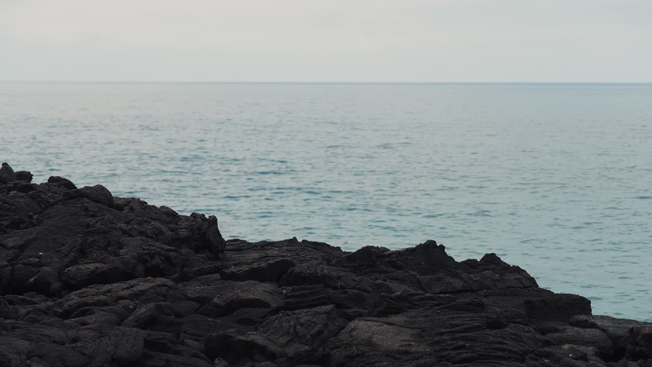 Rocky volcano coastline with hard black rock and blue sea