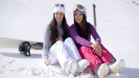 Two-young-women-sitting-waiting-in-the-snow