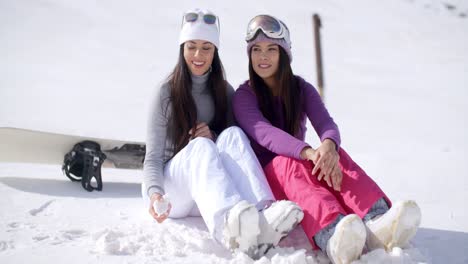 two young women sitting waiting in the snow