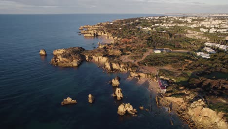 Aerial-view-orbiting-Praia-dos-Arrifes-rocky-coastal-beach-formations,-Scenic-Portuguese-vacation-travel-destination