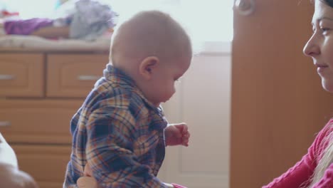 mamá trata de abotonar la camisa del niño en la cama y la hermana en la habitación