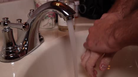 close up and tilt of running faucet and scrubbing hands