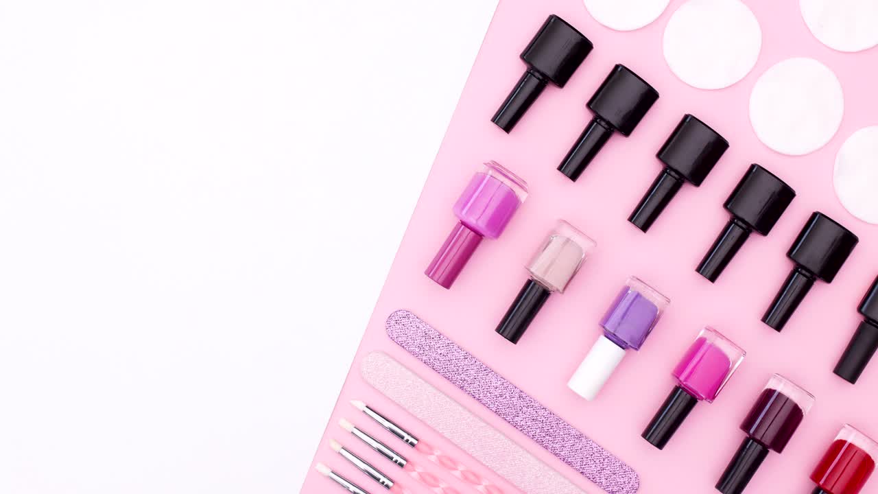 Nail polishes and manicure tools move on pink right side of pink white theme. Stop motion