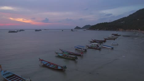 puesta de sol sobre el océano con barcos en la playa