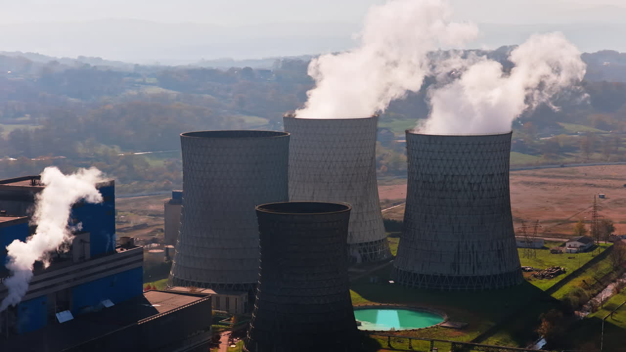 Vista aerea da drone di diverse grandi torri di raffreddamento che rilasciano vapore nell'aria presso la centrale elettrica di Tuzla