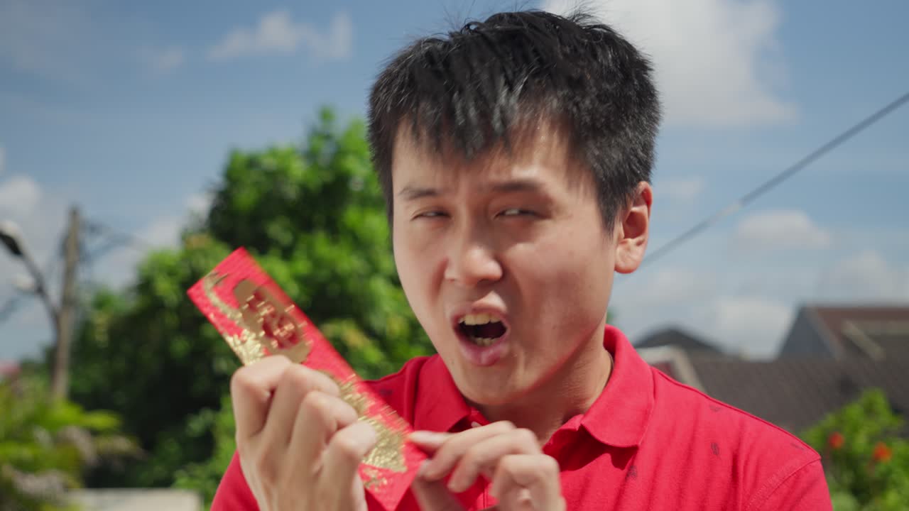 중국인 남자가 흥분하여 중국 신년을 상징하는 활기찬 은 홍바오를 들고 있습니다.