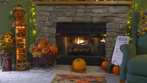 a view of a fireplace with a fire going, all decorated for autumn with pumpkins, scarecrows and fall leaves