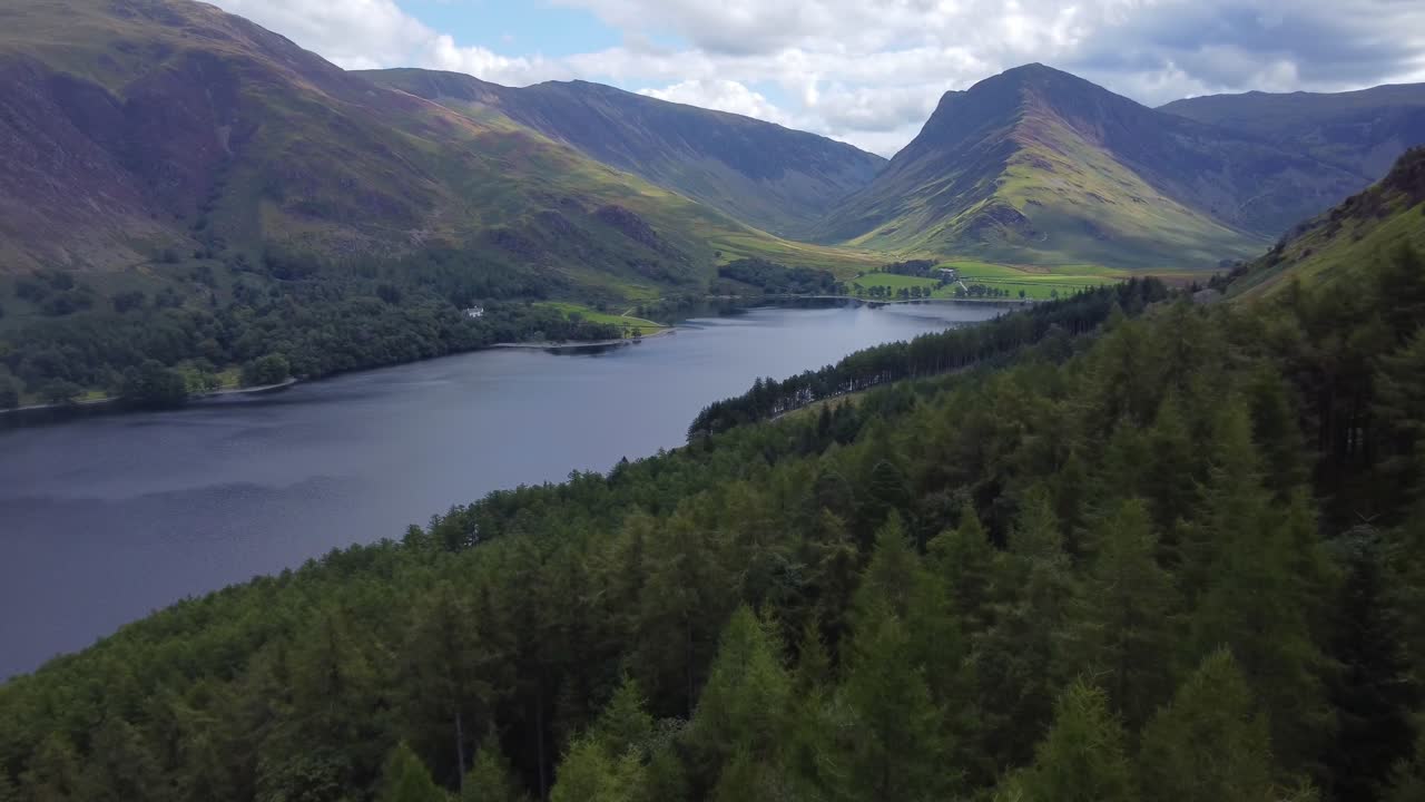 Immersive cinematic shot in idyllic landscape of forest with a lake and fells in Buttermere, Lake District, UK