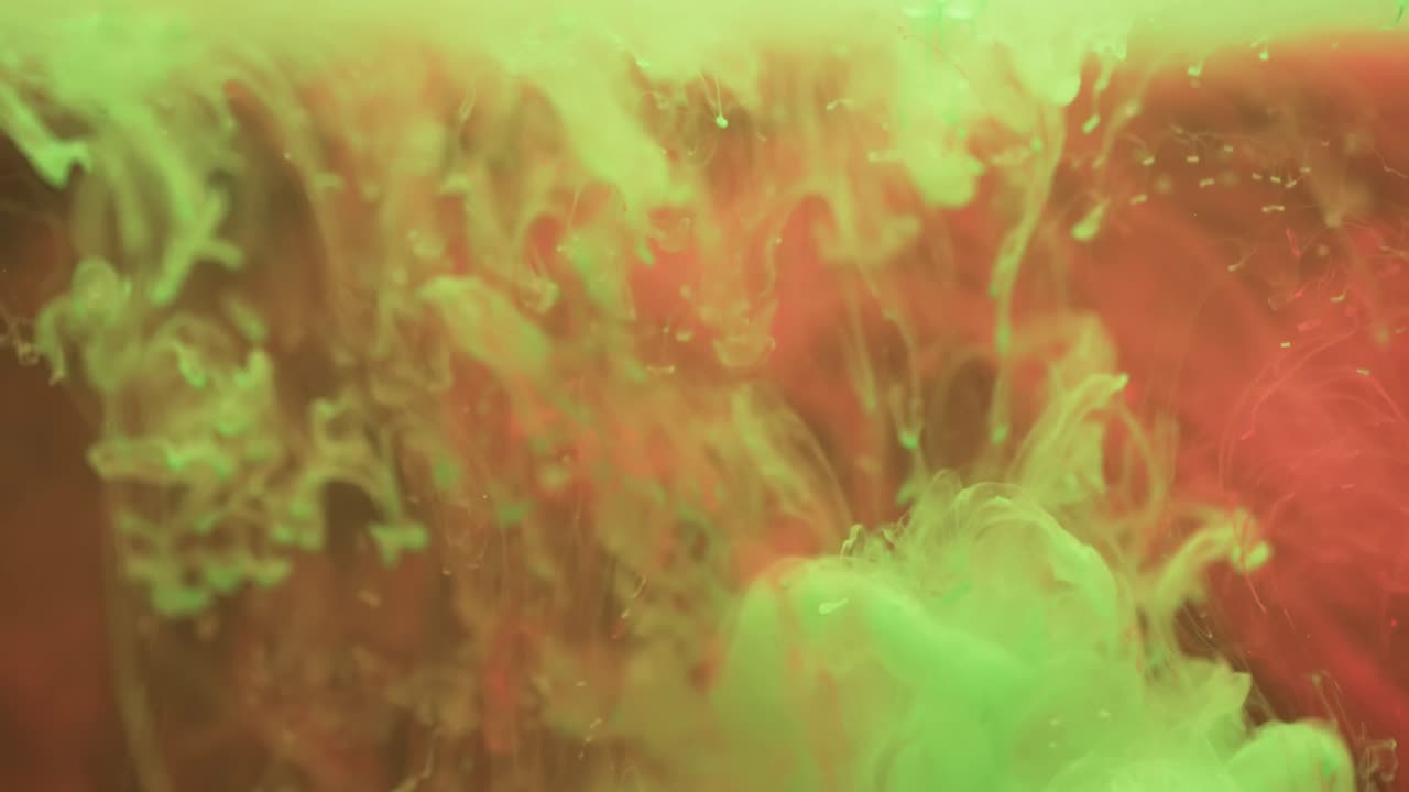 video de primer plano de tinta verde y roja en el agua con espacio de copia